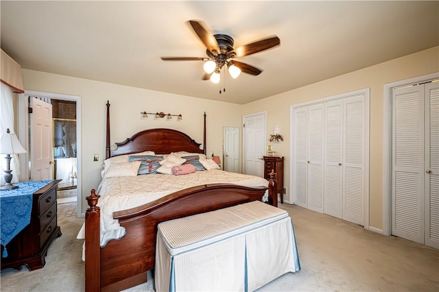 carpeted bedroom featuring multiple closets and ceiling fan