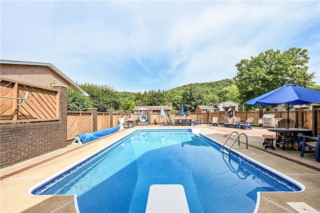 view of pool featuring a diving board and a patio area