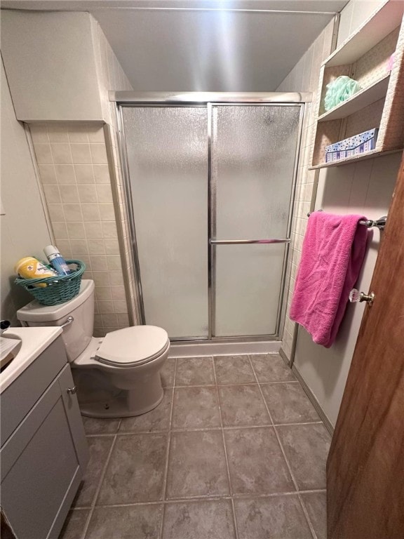 bathroom featuring toilet, walk in shower, tile patterned flooring, tile walls, and vanity