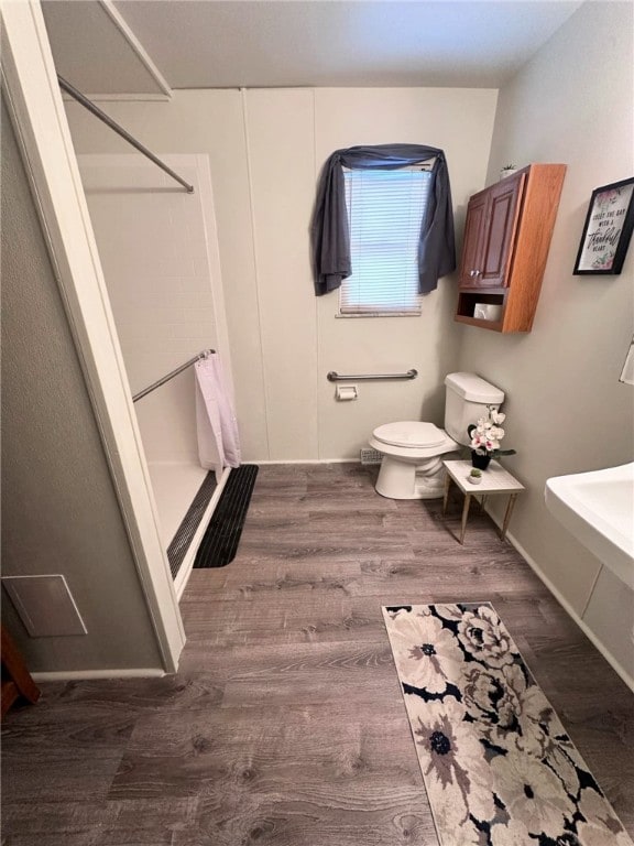 bathroom with toilet, a shower, and hardwood / wood-style flooring