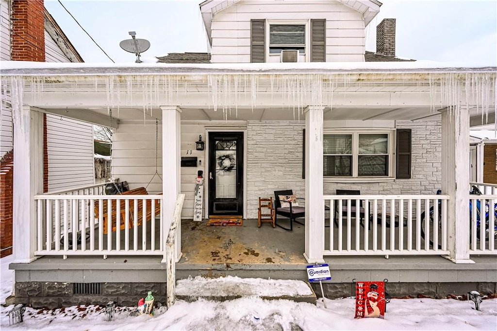 snow covered property entrance featuring a porch