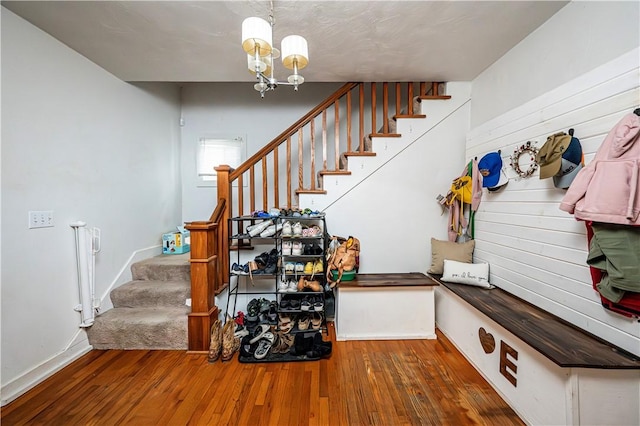 stairway with hardwood / wood-style flooring, an inviting chandelier, and radiator