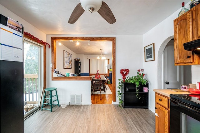 kitchen with electric range, hanging light fixtures, light wood-type flooring, extractor fan, and ceiling fan with notable chandelier