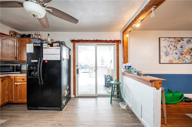 kitchen with black fridge, light wood-type flooring, and ceiling fan