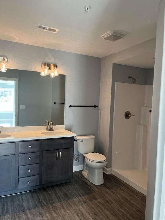 bathroom with toilet, a shower, vanity, and hardwood / wood-style floors