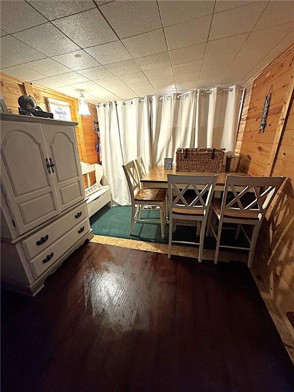 dining room featuring dark wood-type flooring and wood walls