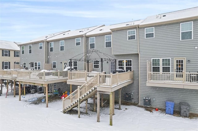 snow covered rear of property with central AC unit, a wooden deck, and a gazebo