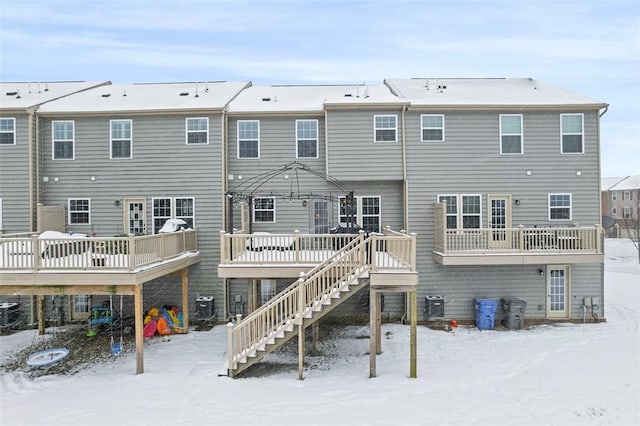 snow covered back of property featuring a wooden deck, central air condition unit, and a gazebo