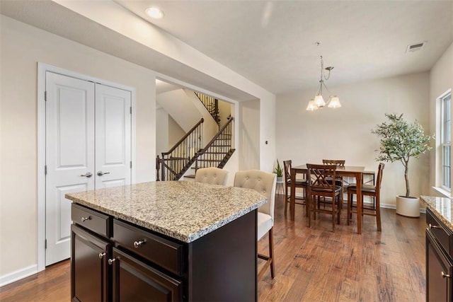 kitchen with a kitchen bar, a notable chandelier, dark hardwood / wood-style flooring, a kitchen island, and pendant lighting