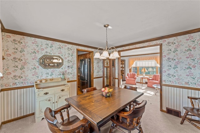 carpeted dining space with a notable chandelier and crown molding