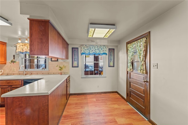 kitchen featuring decorative backsplash, light wood-type flooring, a healthy amount of sunlight, and kitchen peninsula