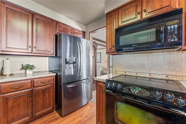 kitchen with black appliances, light hardwood / wood-style flooring, and backsplash