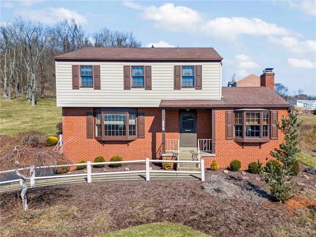 view of front of property featuring a front yard, a chimney, fence, and brick siding