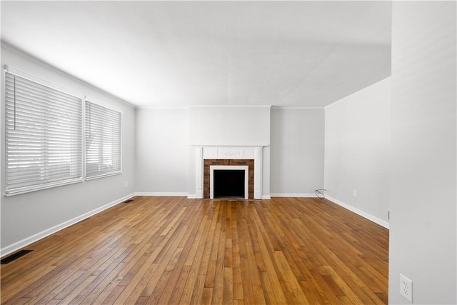 unfurnished living room with a tiled fireplace, light hardwood / wood-style floors, and crown molding