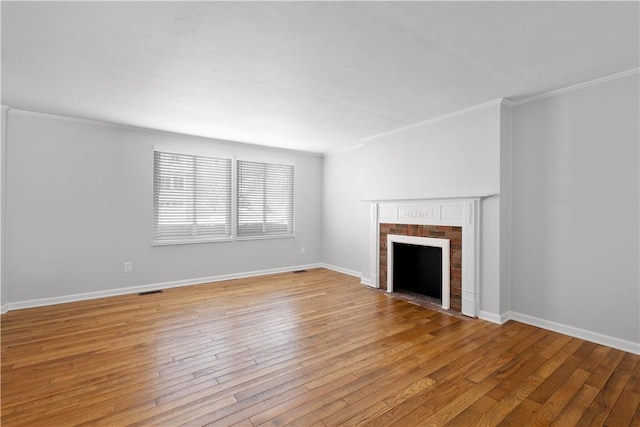 unfurnished living room with ornamental molding, light wood-type flooring, and a brick fireplace