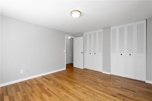 unfurnished bedroom with two closets and light hardwood / wood-style flooring