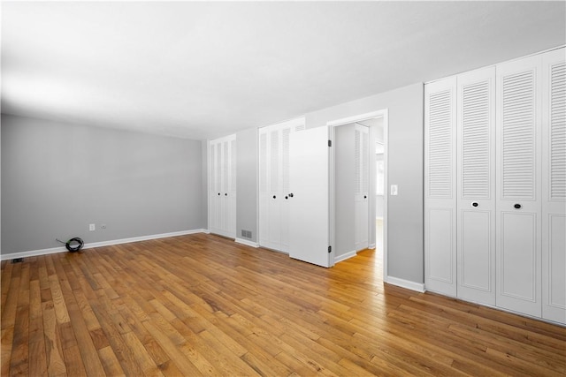 unfurnished bedroom with multiple closets and light hardwood / wood-style floors