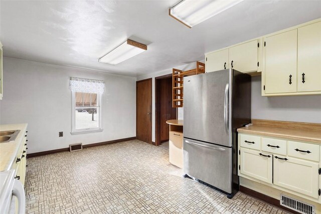 kitchen with sink, cream cabinets, and stainless steel refrigerator