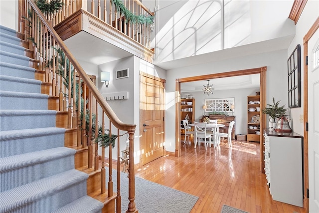 staircase with a high ceiling, a chandelier, and hardwood / wood-style floors