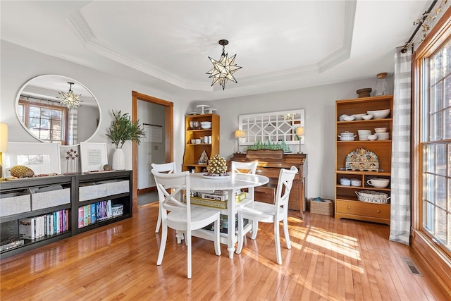 dining area featuring a tray ceiling, light hardwood / wood-style floors, and a chandelier