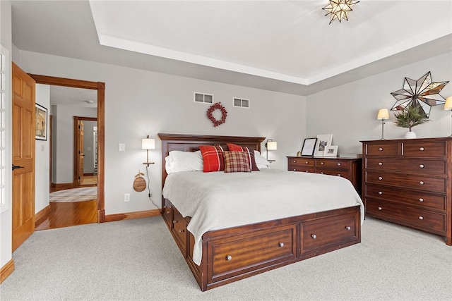 carpeted bedroom featuring a raised ceiling