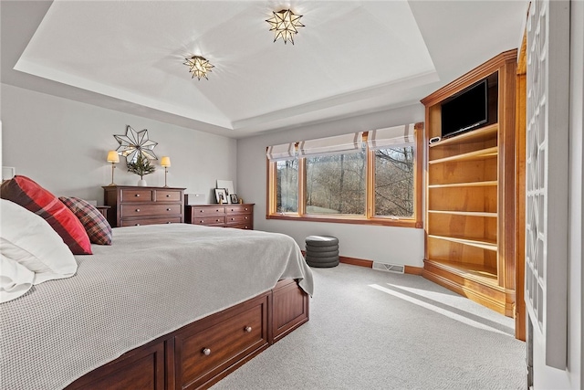 bedroom featuring light colored carpet and a tray ceiling