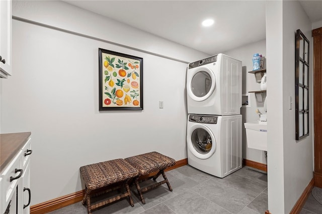 laundry area with stacked washer / drying machine and cabinets