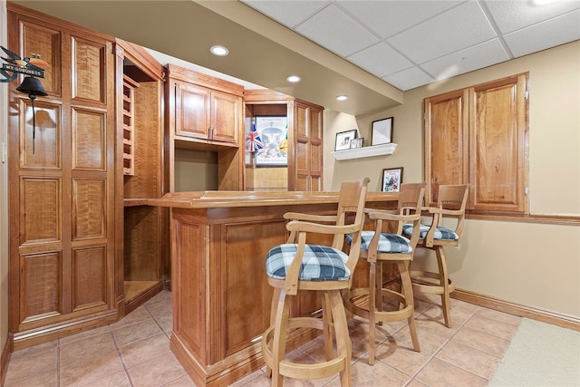 bar with a drop ceiling and light tile patterned flooring