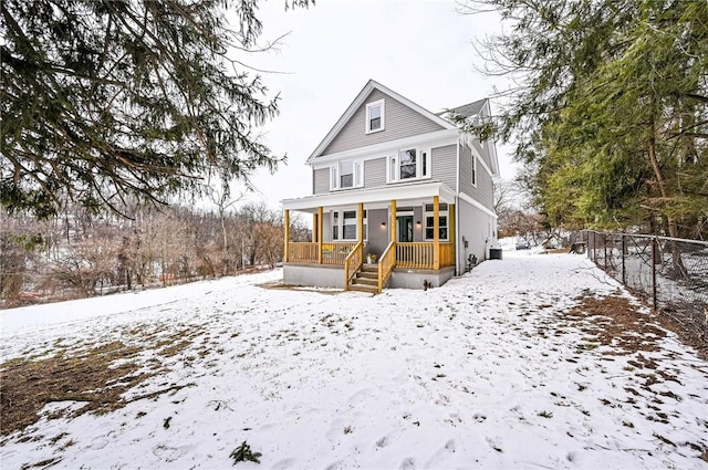 snow covered house featuring a porch