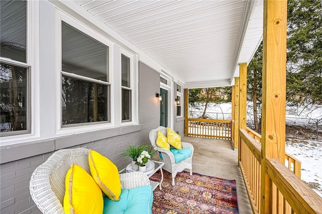 snow covered deck featuring covered porch