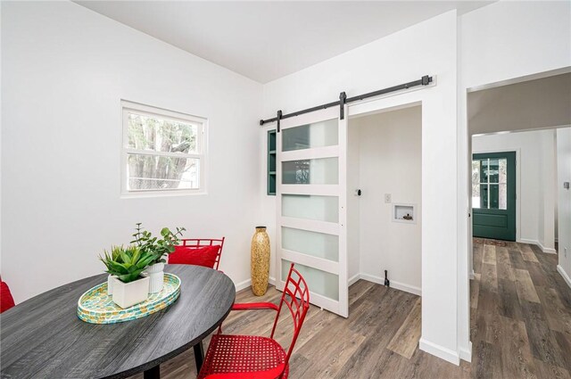 dining space with hardwood / wood-style flooring and a barn door