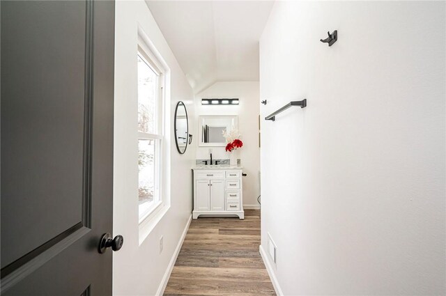 hallway with sink, hardwood / wood-style floors, and lofted ceiling