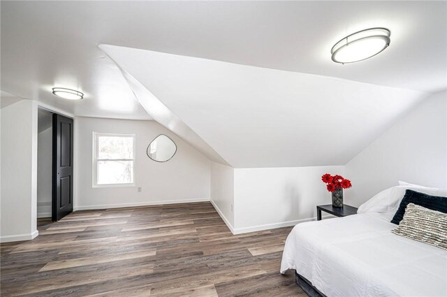 bedroom with dark wood-type flooring and vaulted ceiling