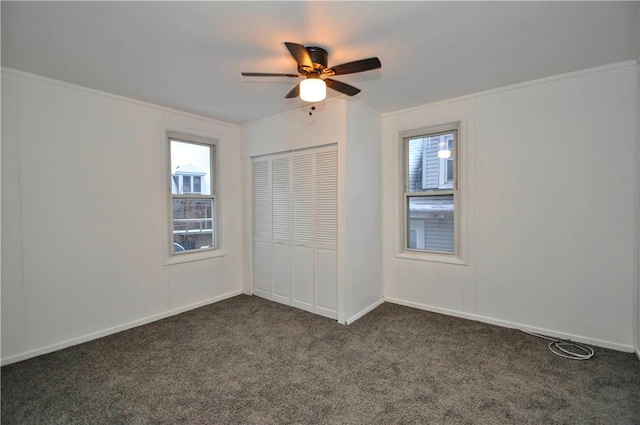 unfurnished bedroom with a closet, ceiling fan, ornamental molding, and dark colored carpet