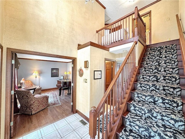 stairway with wood-type flooring and a high ceiling