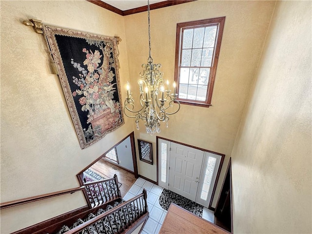 tiled foyer entrance featuring a high ceiling, an inviting chandelier, and ornamental molding