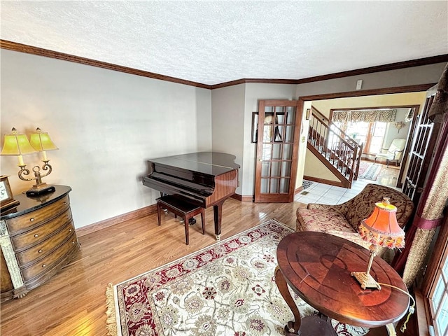 sitting room with a textured ceiling, ornamental molding, french doors, and light wood-type flooring