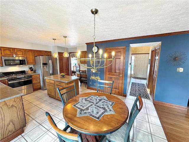 dining area with a textured ceiling, ornamental molding, a notable chandelier, and light tile patterned flooring