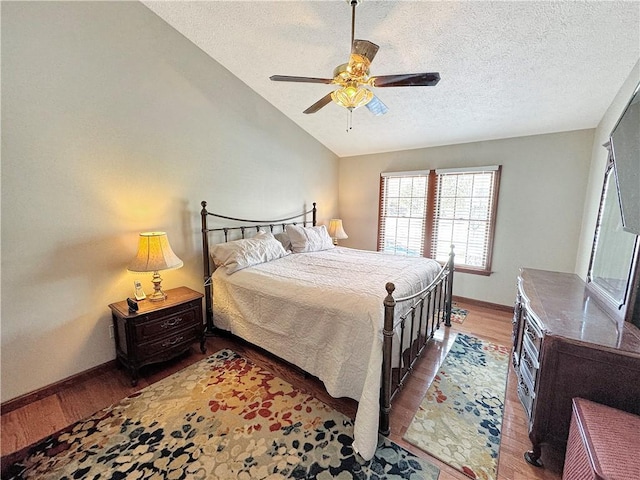 bedroom with ceiling fan, dark hardwood / wood-style floors, a textured ceiling, and lofted ceiling