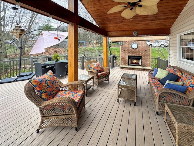 wooden terrace featuring ceiling fan and an outdoor living space with a fireplace