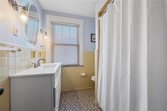 bathroom with toilet, tile patterned floors, vanity, and tile walls