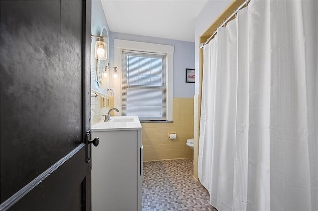 bathroom featuring tile walls, toilet, and vanity