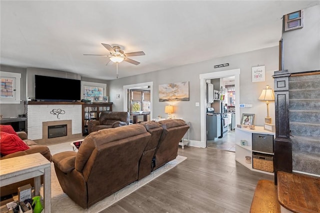 living room featuring ceiling fan, a fireplace, and hardwood / wood-style flooring