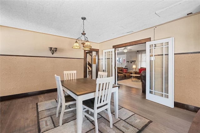 dining space with ornamental molding, french doors, a textured ceiling, and wood-type flooring