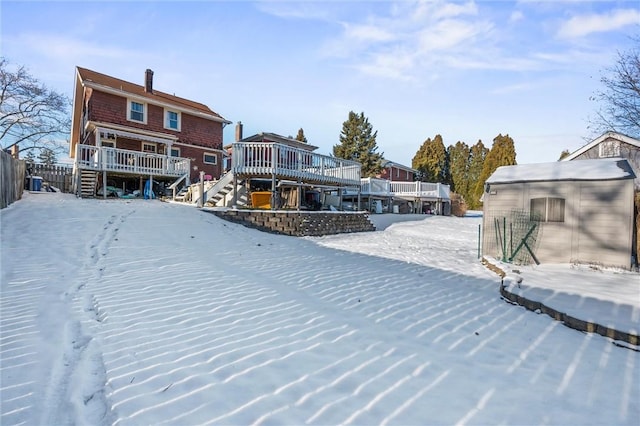 snow covered house with a storage unit and a wooden deck