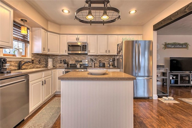 kitchen with sink, stainless steel appliances, white cabinetry, and a center island