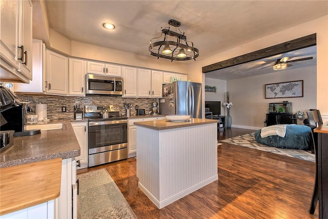 kitchen featuring appliances with stainless steel finishes, white cabinetry, hanging light fixtures, and a center island