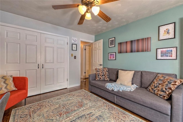 living room with ceiling fan and dark wood-type flooring