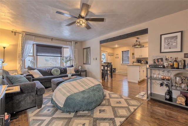 living room with a baseboard heating unit, ceiling fan, and dark hardwood / wood-style floors