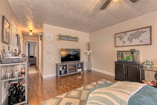 living room with a textured ceiling, ceiling fan, and dark hardwood / wood-style flooring